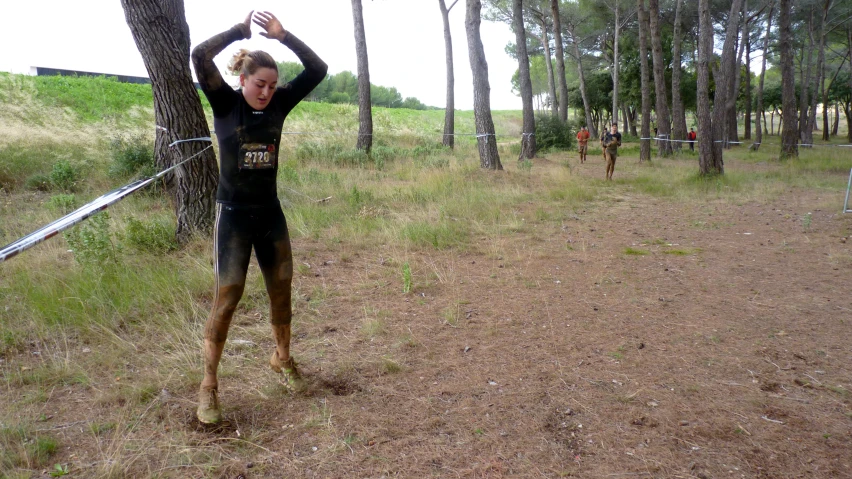 man in wetsuit holding up his arms to catch a frisbee