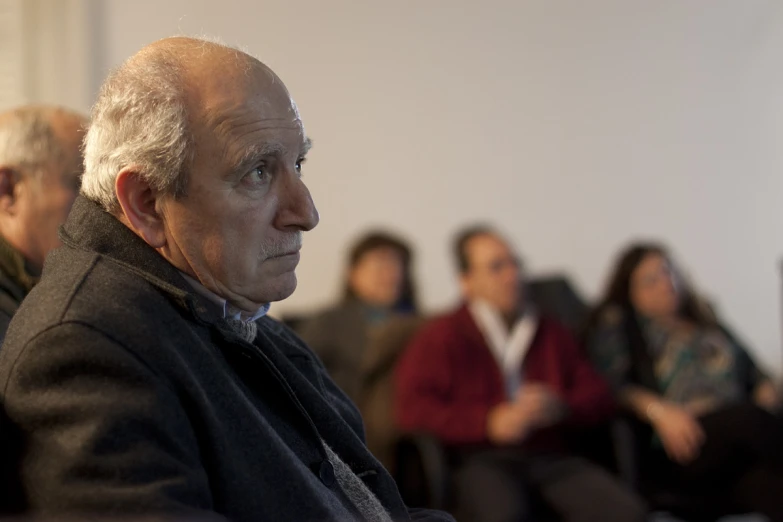 several people sitting down in a row with one man staring at the camera