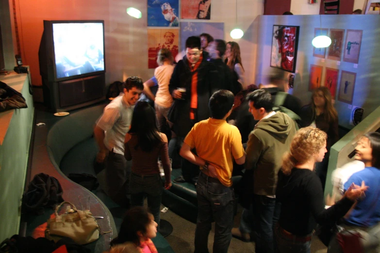 group of people standing in the corner watching soing on the television