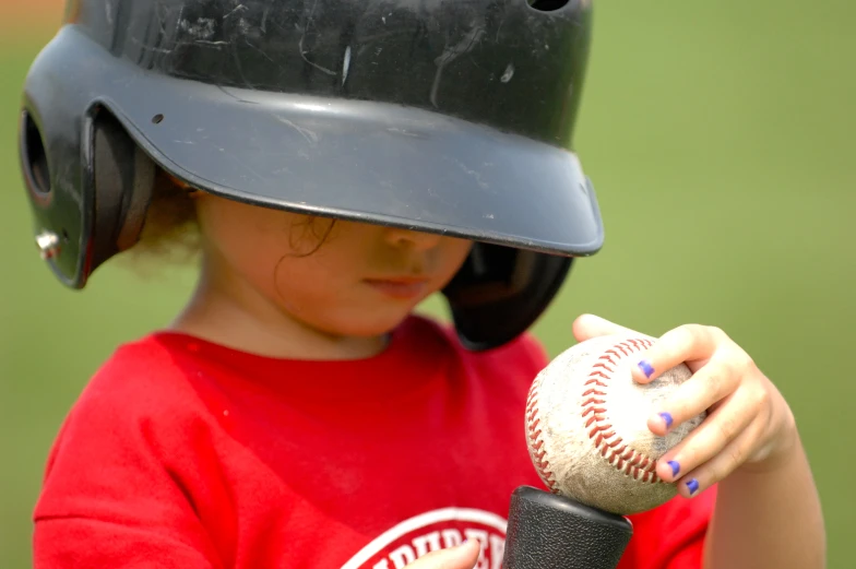 a boy is wearing a black helmet holding a baseball