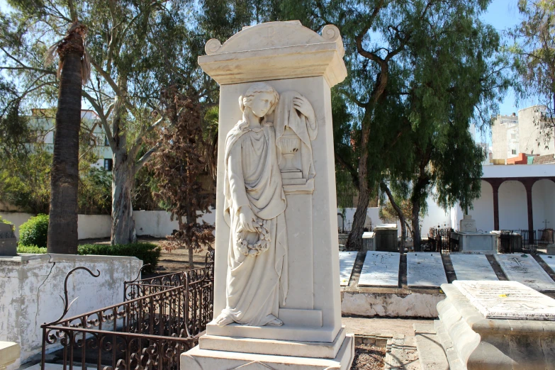a white statue stands in front of some old tombstones