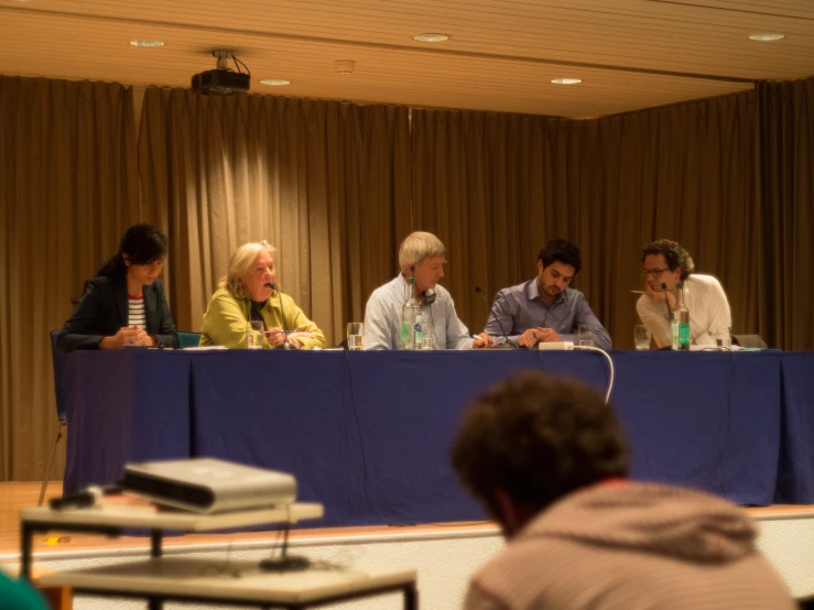 a group of people sit at a table on blue sheets