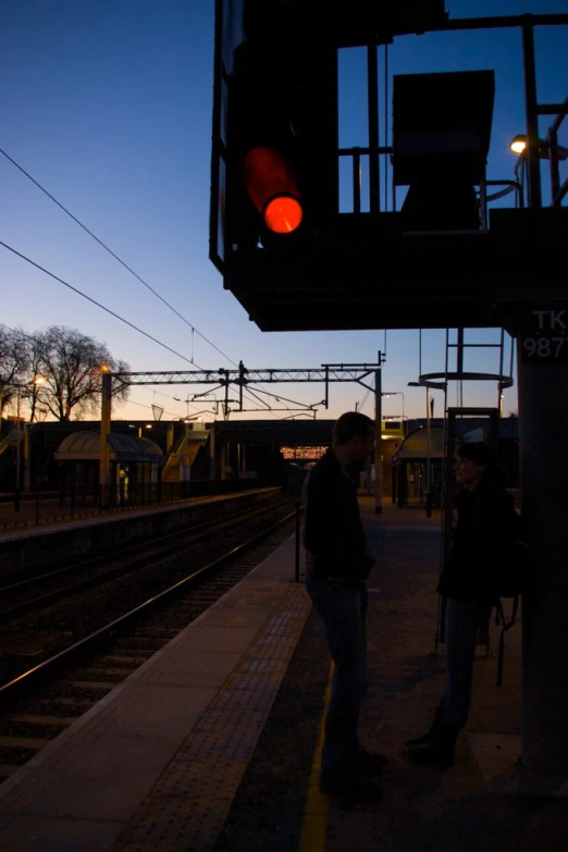 a couple is standing next to train tracks