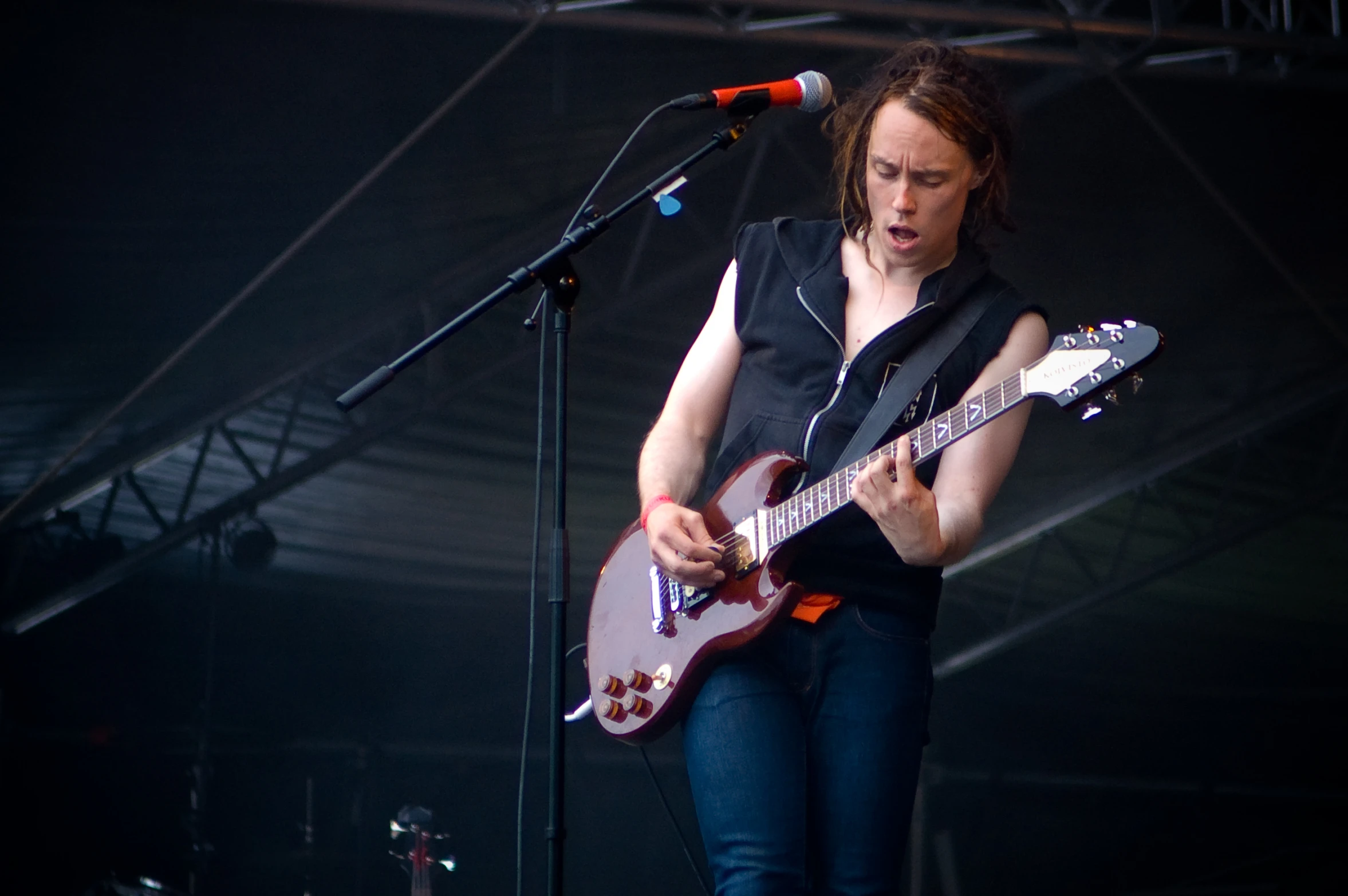 a woman standing on a stage playing guitar