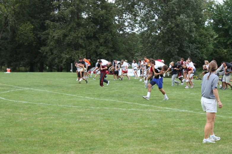 a group of people stand in a grassy field near trees