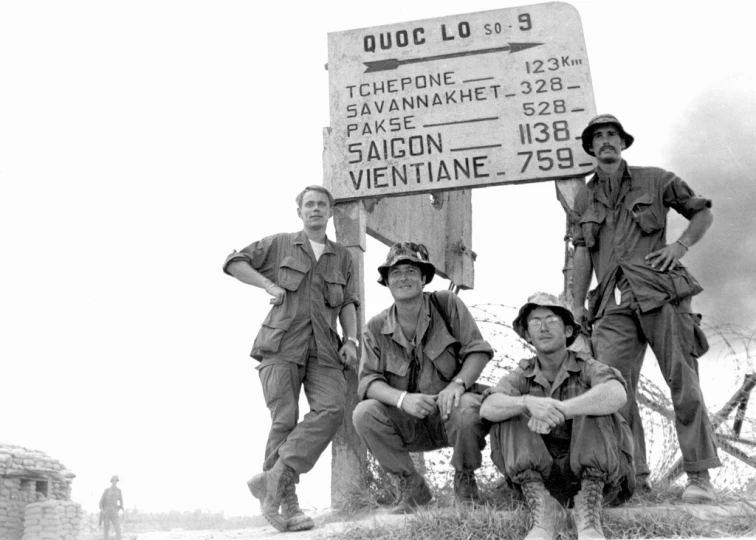 the three soldiers are posing in front of the sign