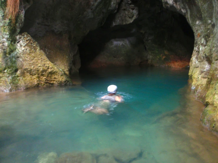 a group of people floating in the water inside of a cave