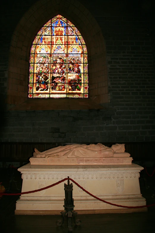 a statue sitting next to a large stained glass window