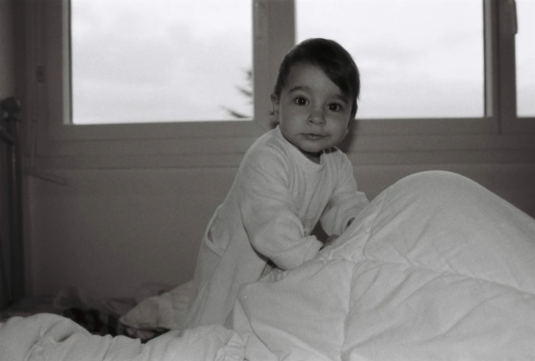 black and white pograph of a young child on a bed