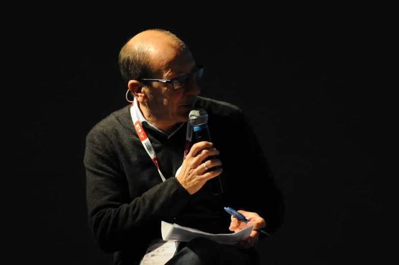 a man standing up while talking into a microphone