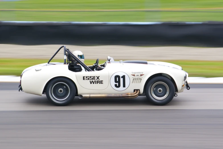 an old white race car is driving on the road