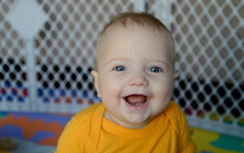 a baby in a yellow shirt with blue eyes
