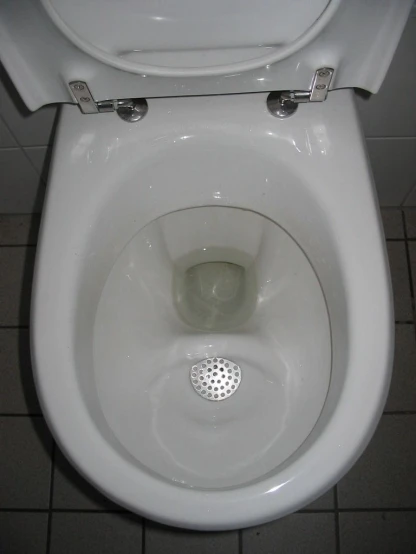 the bowl of a toilet is in a small tiled area