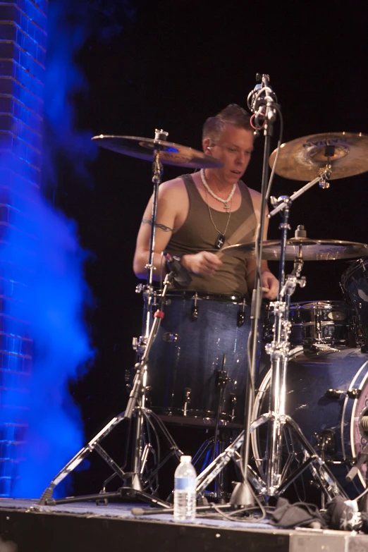 a man standing behind a drum set on top of a stage