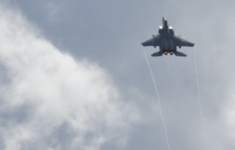 a fighter jet flying through a cloudy sky