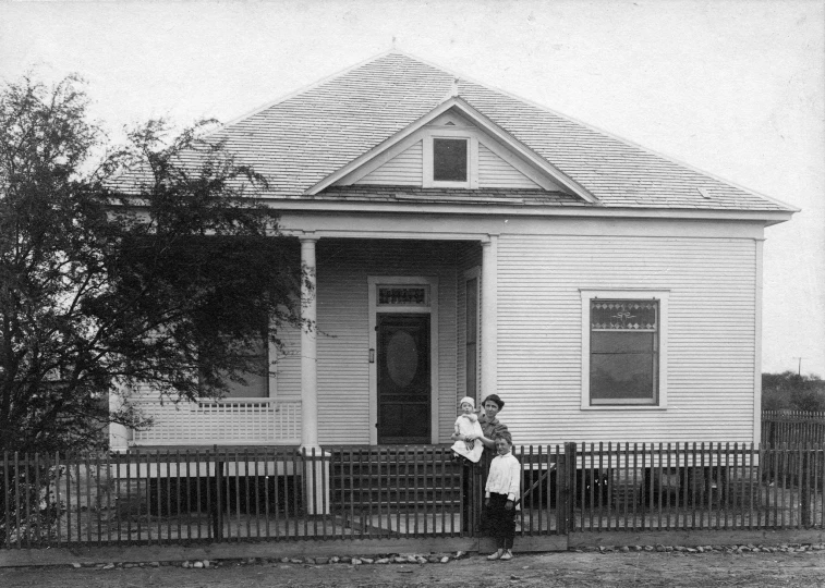 two people standing outside of a white house