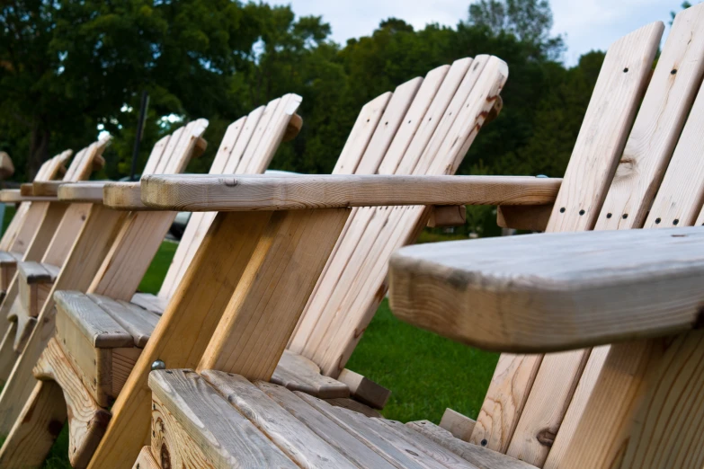 a row of wooden adiron chairs in a grassy field