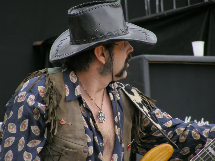 a man in hat and shirt playing an electric guitar