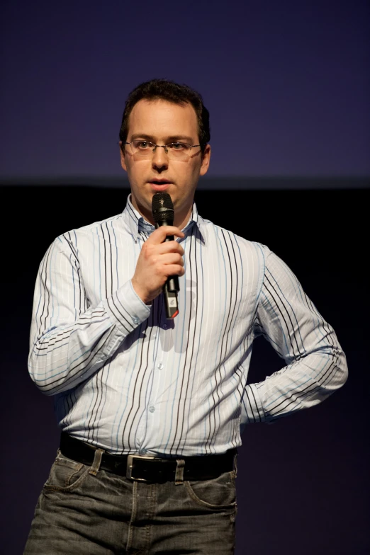 the man is talking into the microphone as he stands