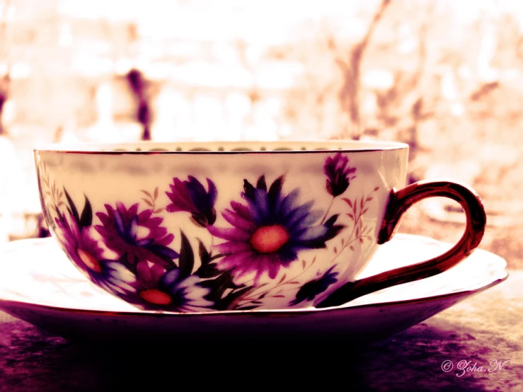 a purple flowered tea cup sits on a saucer