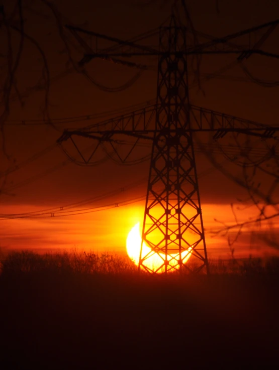 the sun is setting behind an electrical tower