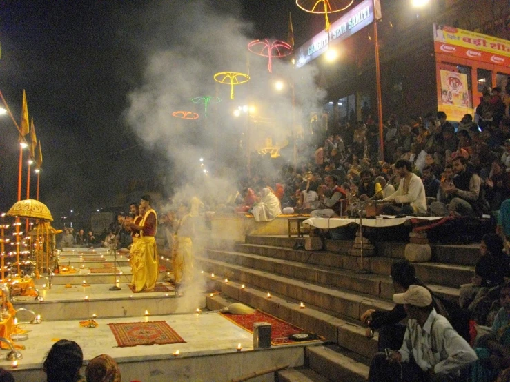 a large audience sits on the steps, watching two monks in white robes