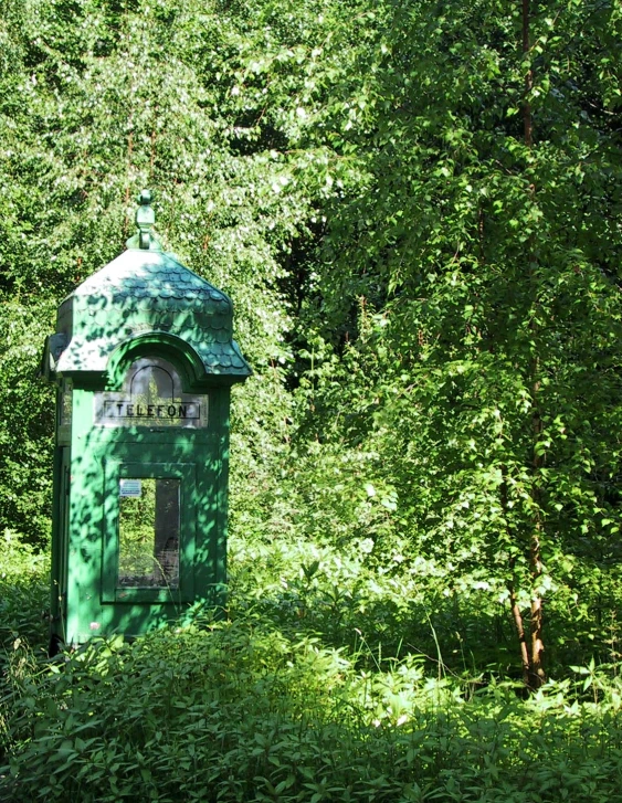 a green restroom in a forest with lots of trees