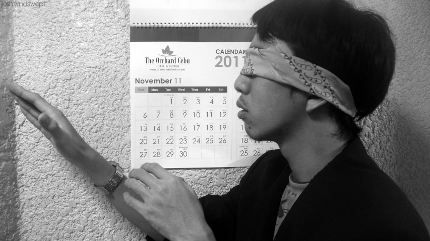 an asian man has his eye drawn on a calendar