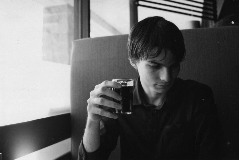 a man drinking an alcoholic beverage sitting in a booth