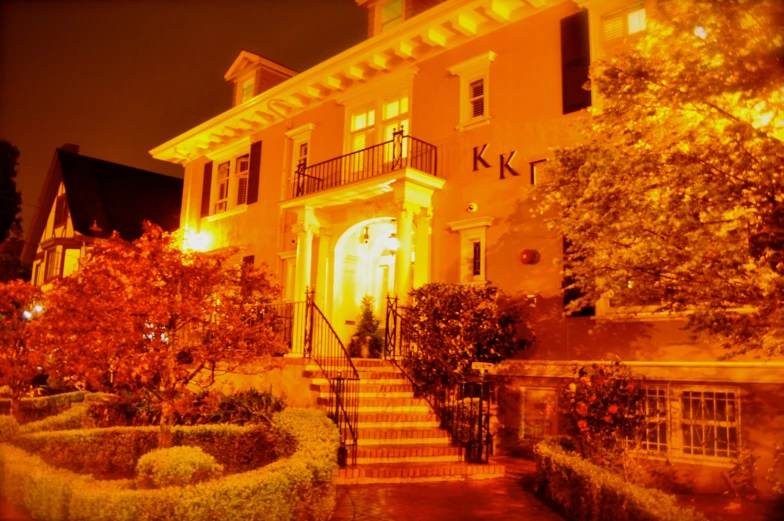 the night time view of a large home with lighted front door and stairs