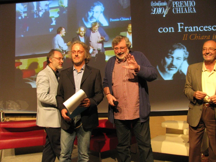 four men standing around at a presentation in front of a projector screen