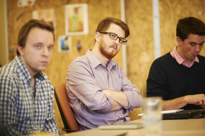 three men in the process of meeting in a small room