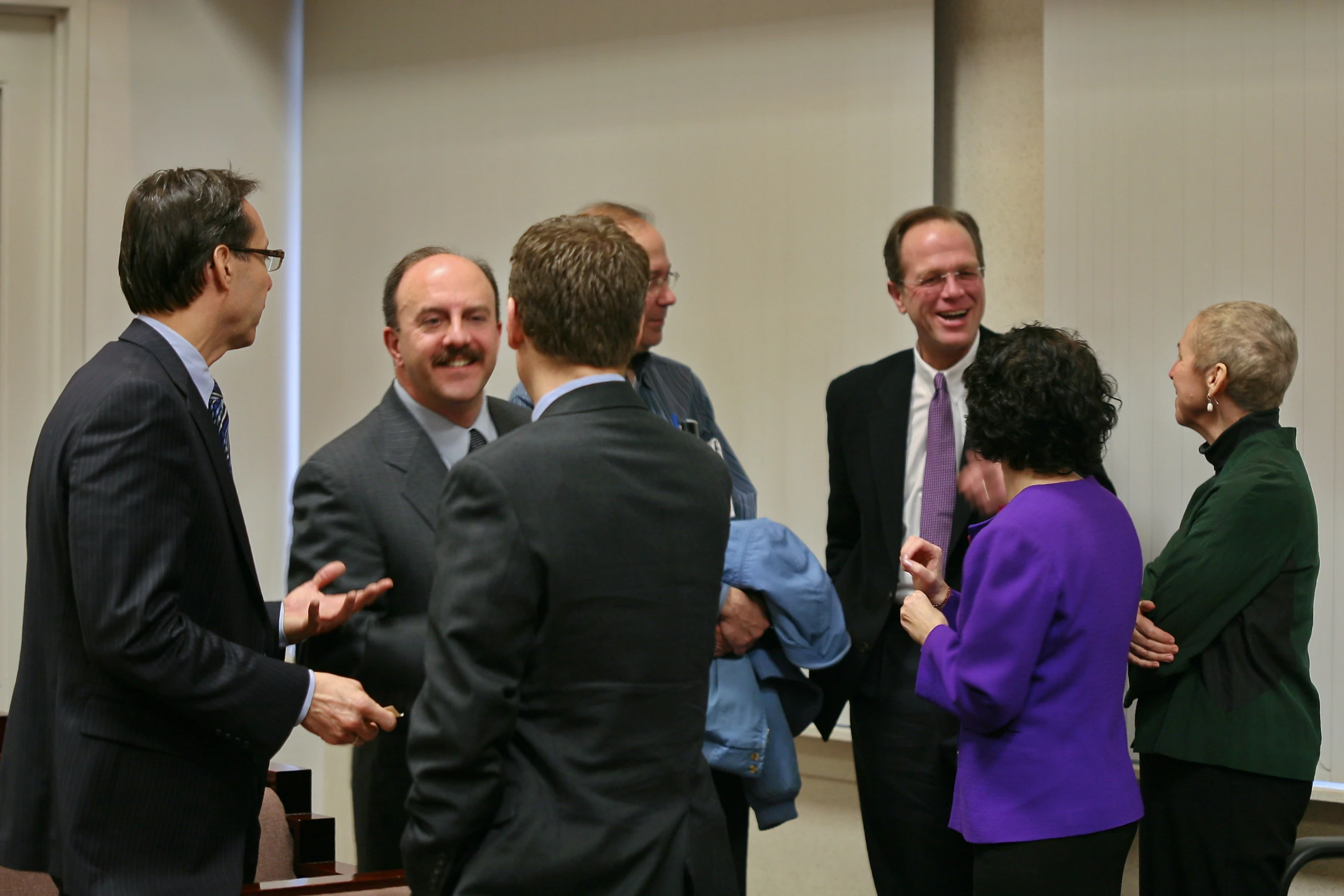 several business people stand in a room talking