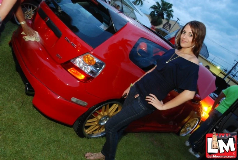 a woman posing for the camera in front of a red car