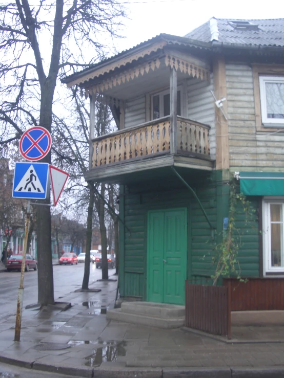 this is a house on a street corner with green doors and balconies
