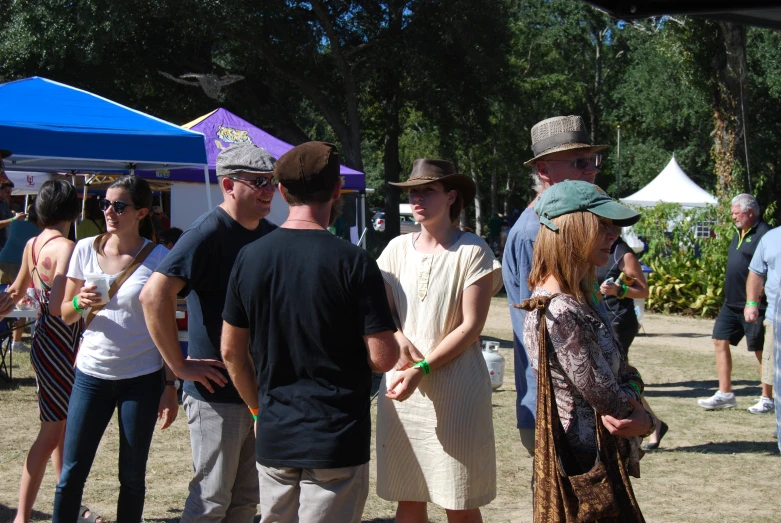 people stand together under some tents at a park