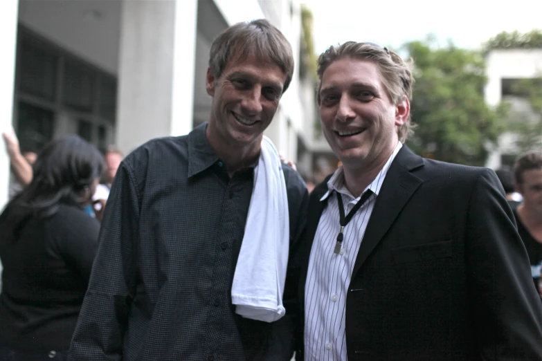 two men smiling in front of a crowd of people