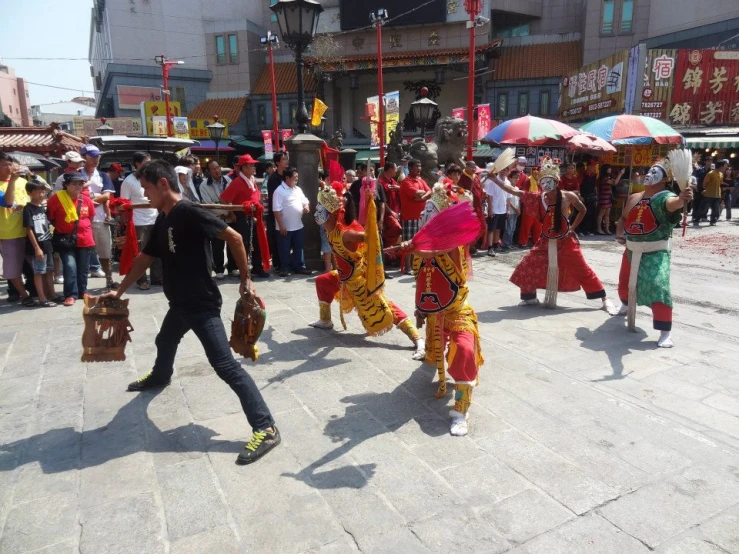an asian festival is performing in the center of a crowded street
