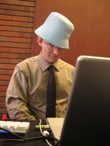 man wearing blue hat sitting in front of a computer