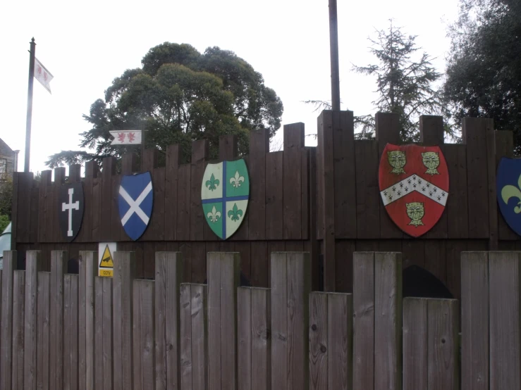 several shields are on the fence of a village