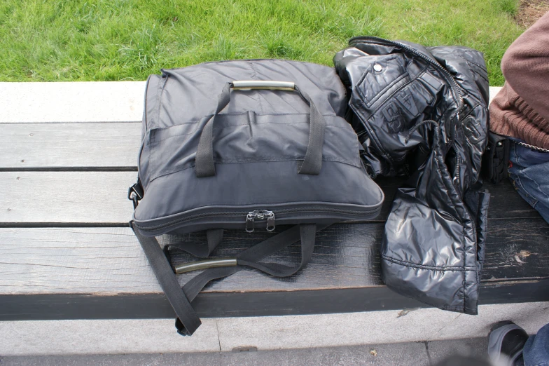 a bag and luggage on a park bench