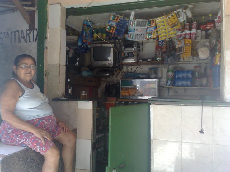 a women sitting in front of a food stand with food