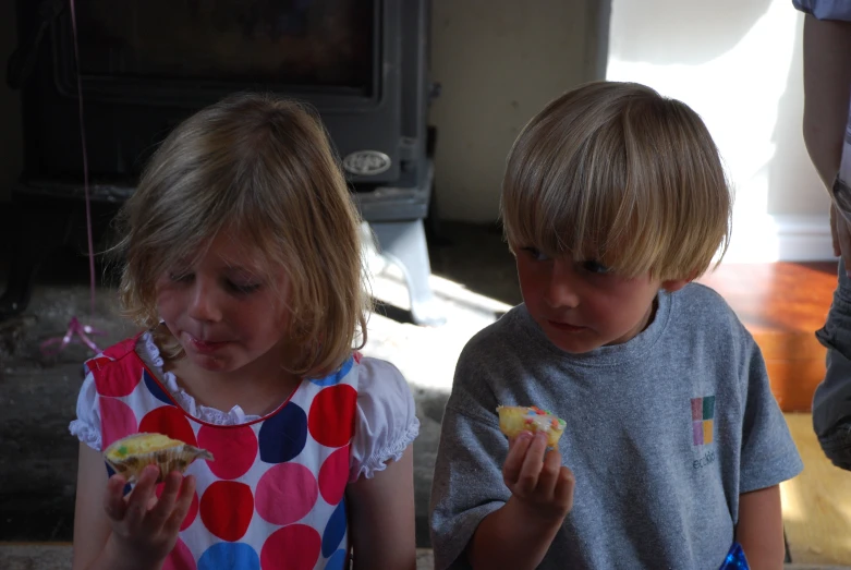 two young children sitting next to each other eating