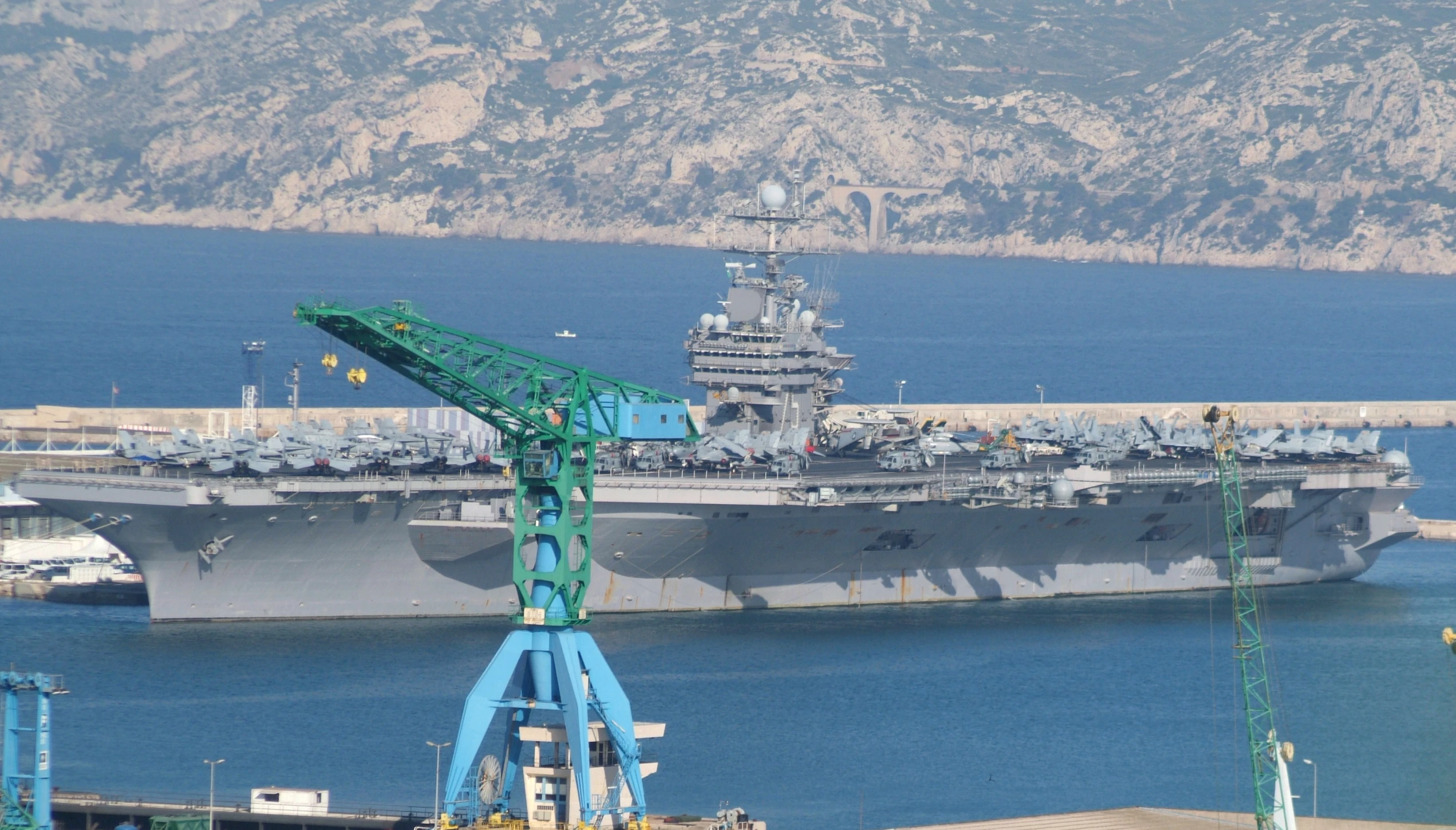 large military ship docked in the water near docks