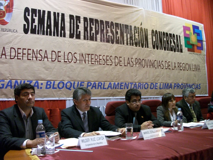 four men in suits and ties sitting at a table