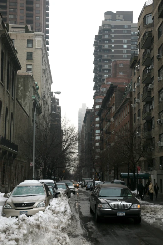 several cars are parked in the snow in a row on the side of the road