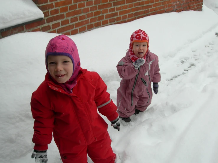 two small children walking through the snow with their shoes on