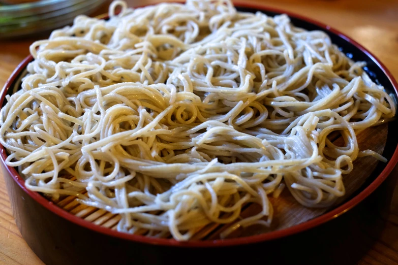 a bowl of cooked noodles sits on a table