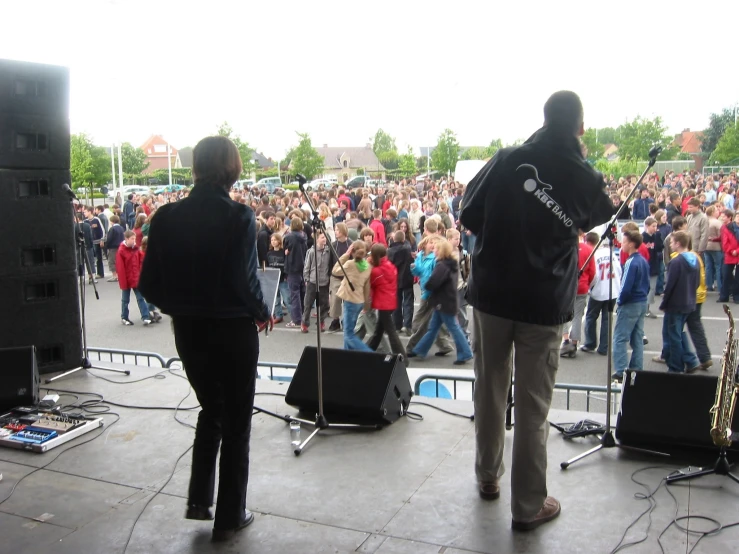 two men performing on stage with large crowd watching