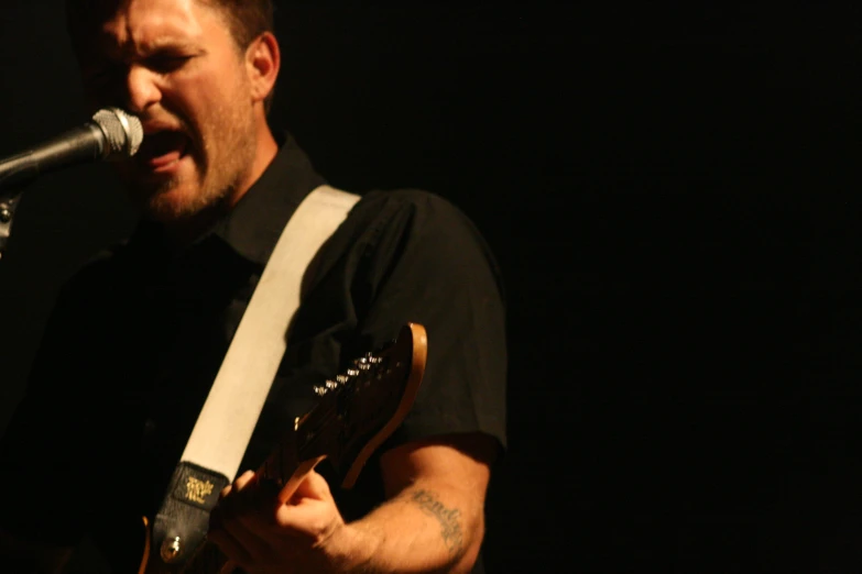 a man with a guitar singing into a microphone